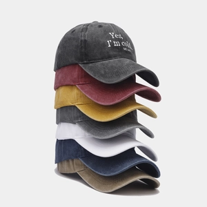 Vertical stack of washed cotton baseball caps in seven colors featuring slogan embroidery