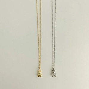 Detailed view of two minimalist bear pendant necklaces in gold and silver finishes