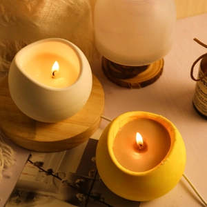 Dettaglio di candele sferiche bianche e gialle su una base in legno naturale