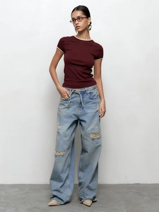 Détail d'un t-shirt en tricot bordeaux avec bordure contrastée et jean large déchiré