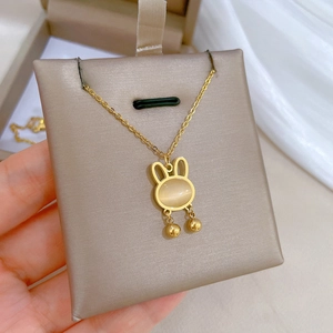 Minimalist gold titanium necklace featuring an opal rabbit pendant on a velvet card