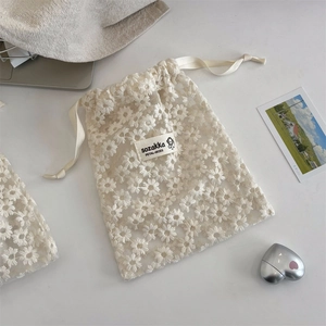 Dettaglio della borsa in pizzo bianco con delicati ricami a forma di margherita