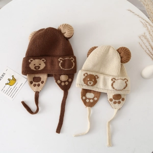 Detail of knitted bear ear hats in brown and cream colors with cute paw prints