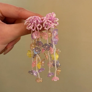 Close-up of colorful beaded flower tassel earrings held in hand for resort style jewelry
