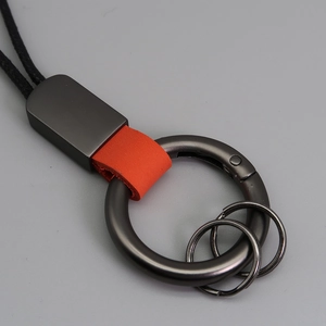 Détail de l'anneau en métal gunmetal et du bracelet en cuir orange du porte-clés
