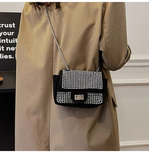 Detail of black suede rhinestone crossbody bag with metal chain strap and twist lock closure