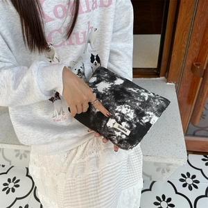Close-up of marble pattern canvas toiletry bag with woven label held by a model