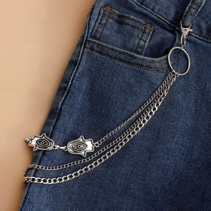 Detail of silver multilayer waist chain with Hamsa hand and evil eye on denim jeans