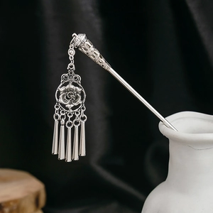 Close-up of silver hair stick with turquoise flower and hanging metallic tassels