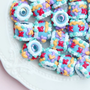 Macro shot of colorful hand-painted resin beads with patterns in a white decorative plate