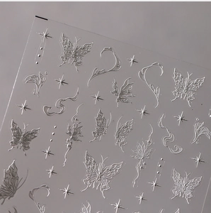 Macro shot of silver embossed butterfly and star nail art stickers with metallic texture