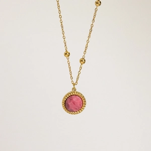 Primer plano del colgante de piedra rosa con borde de cuerda dorada en una cadena de oro