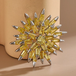 Elegant silver sunburst brooch with radiant yellow crystals on a warm ceramic base
