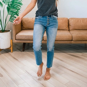 Detail of light blue straight denim jeans with multi-button closure and frayed hem