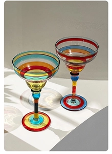 Detail of hand-painted margarita glasses with colorful stripes and light refraction