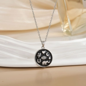 Silver celestial necklace with elephant and moon pendants on a wavy ceramic display