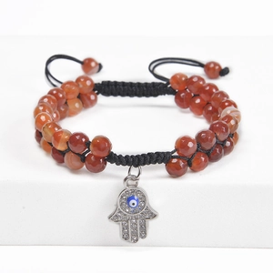 Detail of red beaded Hamsa hand bracelet with sparkling blue evil eye charm