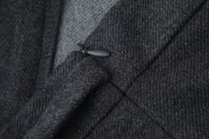 Detail aus weichem dunkelgrauem Twill-Stoff und verdecktem Reißverschluss der Jacke