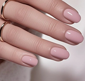 Primer plano de uñas postizas almendradas rosa suave brillante con anillos dorados