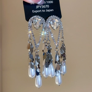 Detail of elegant teardrop pearl earrings with diamonds and layered silver leaves