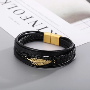 Close-up of multilayer leather bracelet with a gold feather pendant and magnetic clasp