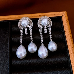 Dettaglio di orecchini stile palazzo vintage con perle e strass su un vassoio