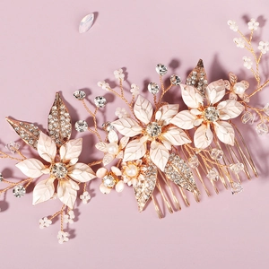 Close-up of golden bridal hair comb with white enamel leaves, pearls and crystals