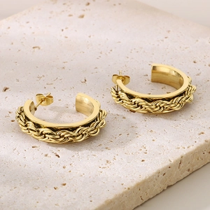 Detailed close-up of C-shaped gold hoop earrings with braided rope texture on stone base