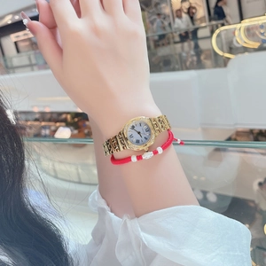 Detail of elegant gold-toned watch with diamond bezel and red woven bracelet set
