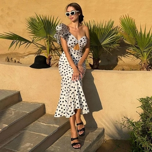 Close-up of white polka dot swimsuit featuring ruffled one-shoulder and cutout detail