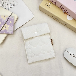 Detailed view of white quilted heart-pattern pouch with snap closure on a desktop