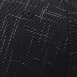 Detailed close-up of black baseball cap fabric with grey grid texture and vent hole