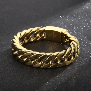 Polished gold stainless steel Cuban link bracelet with flat buckle on black surface