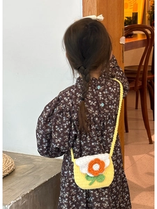 Detail of yellow handmade crochet flower bag with lace trim on a young child's shoulder