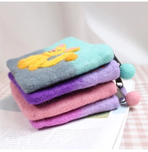 Close-up of handmade wool felt coin purses with cat embroidery and pompom zippers
