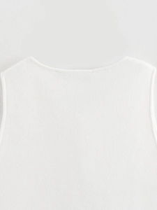 Gros plan détaillé du gilet en tricot blanc montrant la texture et l'encolure