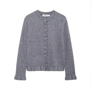 Detailed close-up of a grey knit cardigan featuring small buttons and a ruffle trim