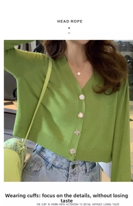 Close-up of four-leaf clover and smiley face buttons on a green knit cardigan