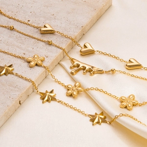 Detail view of gold bracelets with heart, star, flower and fluid drop charms on silk