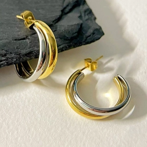 Detail shot of two-tone interlocking C-hoop earrings with gold and silver polished finish