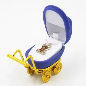 Blue velvet baby stroller jewelry box with gold trim featuring a reindeer pendant necklace