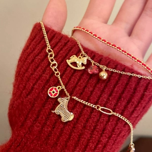 Detail of gold horse charm and red heart gemstone bracelet on red knit background