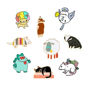 Flat lay detail of nine cartoon animal enamel pins including cats and dinosaurs