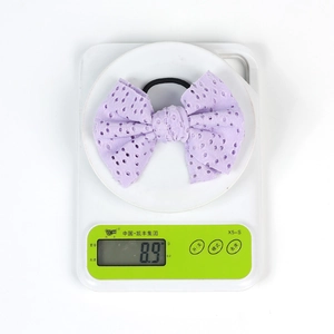 Detail shot of purple eyelet lace bow hair tie on digital scale weighing 8.9 grams