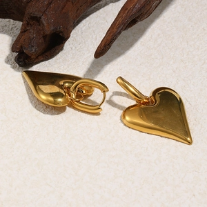 Macro di orecchini a cuore placcati oro 18K su uno sfondo in pietra dal design minimal