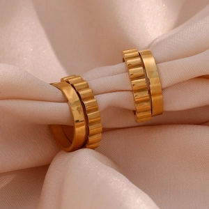 Detailed macro of gold-plated double-layer gear texture C-shaped hoop earrings on satin