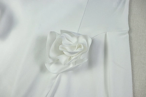 Detail of a large 3D white fabric flower rosette on a minimalist short A-line dress