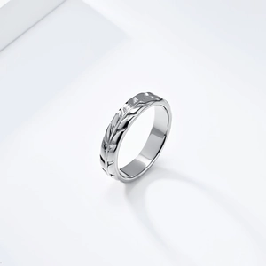 Macro shot of silver stainless steel ring featuring detailed carved leaf patterns