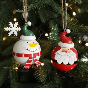 Hand-painted metal Santa and snowman ornaments with sled base on a lit Christmas tree