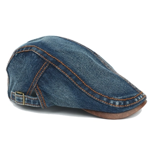 Detail of blue denim ivy cap with orange stitching and brown leather visor brim